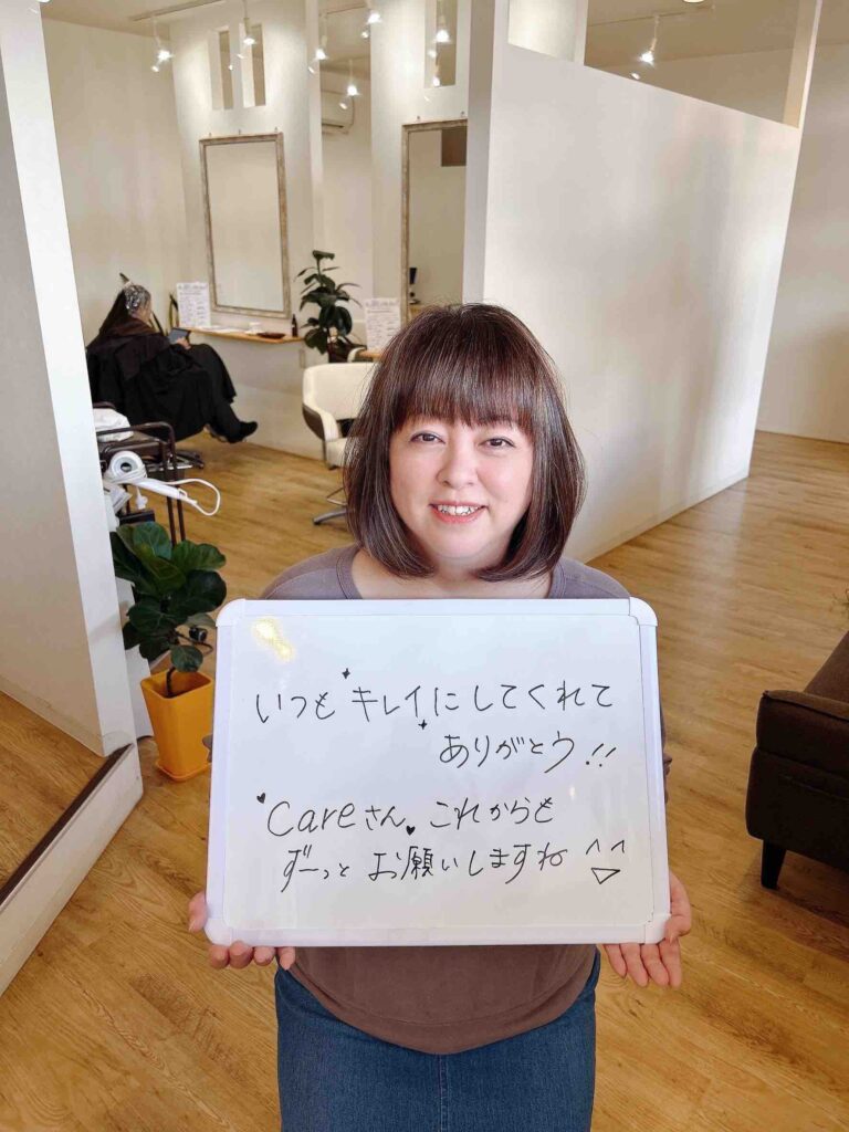 いつもキレイにしてくれてありがとうと、美容室careへ感謝のメッセージを掲げるお客様の笑顔の写真